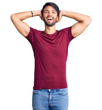 Handsome hispanic man wearing casual clothes relaxing and stretching, arms and hands behind head and neck smiling happy