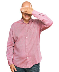 Middle age bald man wearing casual clothes smiling and laughing with hand on face covering eyes for surprise. blind concept.