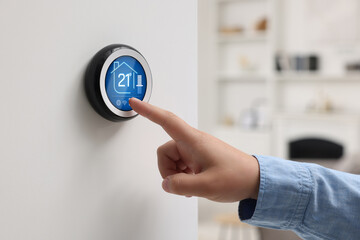 Smart home system. Woman using thermostat indoors, closeup