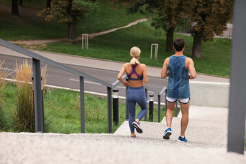 Healthy lifestyle. Couple running down stairs outdoors, back view