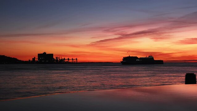 Passenger and vehicle ferry ship vessel silhouette in sea against dramatic sunset sky background in Lisbon, Portugal