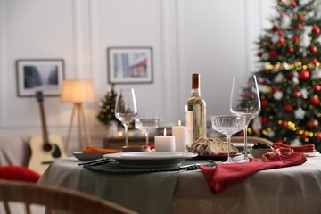 Christmas table setting with burning candles, appetizers and dishware in room