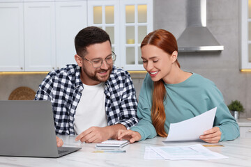 Couple calculating taxes for online payment at table in kitchen