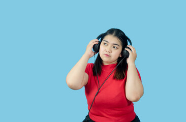 Portrait girl young woman asian chubby fat cute beautiful pretty one person wearing a red shirt, listening to music sound through a smartphone headphone happy fun enjoy in isolated blue blackgrond