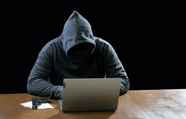 Hacker spy man one person in black hoodie sitting on a table looking computer laptop used login...