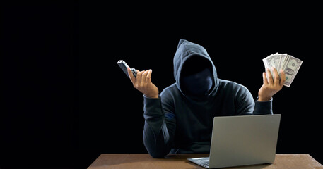 Portrait hacker spy man one person in black hoodie sitting on table looking computer laptop used...
