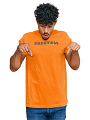 Young arab man wearing tshirt with happiness word message pointing down with fingers showing...