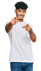 Young arab man wearing casual white t shirt pointing to you and the camera with fingers, smiling positive and cheerful
