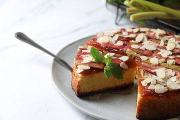 Freshly baked rhubarb pie with almond flakes and cake server on white marble table, closeup