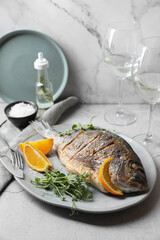 Seafood. Delicious baked fish served with orange and microgreens on light table