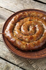 Plate with tasty homemade sausages on wooden table, closeup