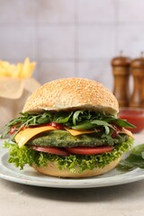 Tasty vegetarian burger with spinach cutlet, cheese and vegetables served on white table, closeup
