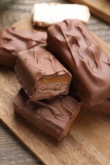 Tasty chocolate bars with nougat on wooden table, closeup