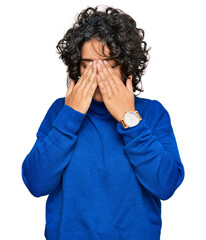 Young hispanic woman with curly hair wearing turtleneck sweater rubbing eyes for fatigue and...