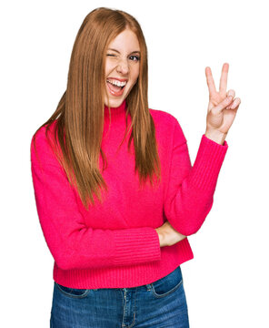 Young irish woman wearing casual clothes smiling with happy face winking at the camera doing victory sign. number two.