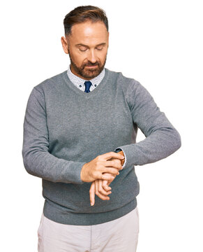 Handsome middle age man wearing business clothes checking the time on wrist watch, relaxed and confident