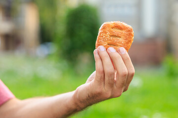 A guy's hand holds a mini puff pastry with cheese, snack and fast food concept. Selective focus on...