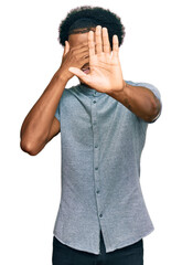 African american man with afro hair wearing casual clothes covering eyes with hands and doing stop gesture with sad and fear expression. embarrassed and negative concept.