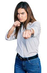 Young caucasian girl wearing casual white shirt punching fist to fight, aggressive and angry attack, threat and violence