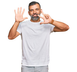 Middle age handsome man wearing casual white tshirt showing and pointing up with fingers number eight while smiling confident and happy.