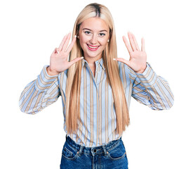 Beautiful blonde woman wearing casual striped shirt showing and pointing up with fingers number...