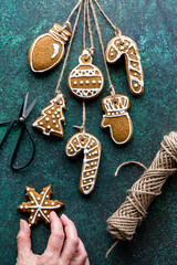 Preparing various gingerbread cookie tree ornaments with twine for hanging.