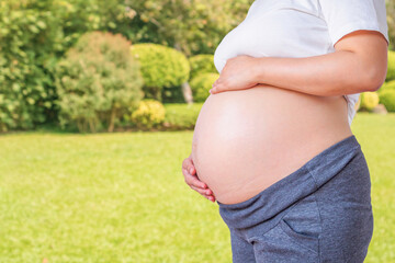 pregnant woman holding her pregnant belly in the garden