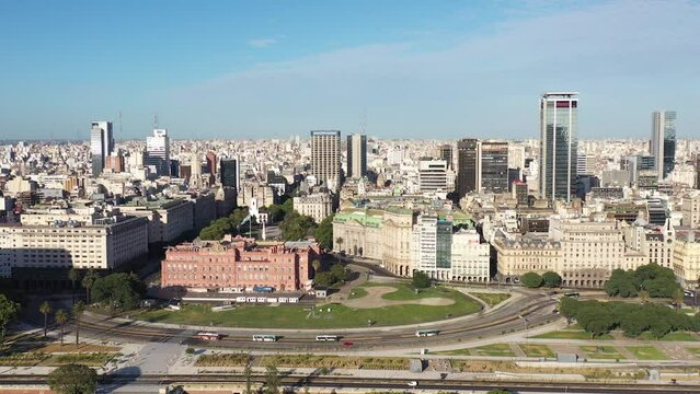 An aerial view of Buenos Aires' Plaza de Mayo, the iconic Casa Rosada, and the city's skyline, under the clear sky