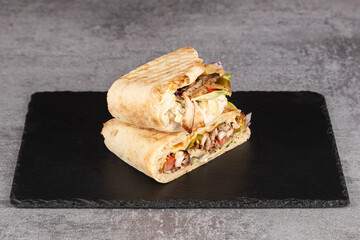 Chicken wraps with tomatoes, pickles, cabbage and onion on chopping board and stone  table....