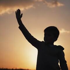 Fototapeta premium Silhouette shot of a child standing against a bright background, with their hand raised