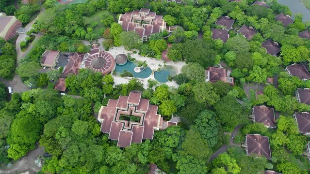 A top-down flyover drone shot over a Resort and Golf Course, having unique Central-American style buildings and rooftops, surrounded by dense jungle, in Northern Costa Rica.