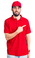 Young handsome man with beard wearing delivery uniform pointing aside worried and nervous with forefinger, concerned and surprised expression