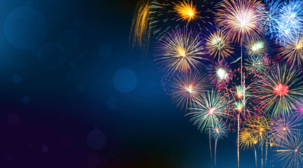 Fireworks of various colors burst on blue background with copy space