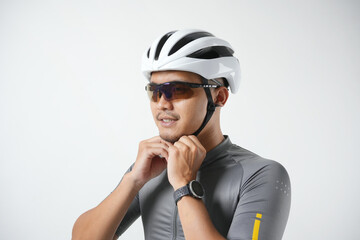 Photo of a sporty young Asian man closing the protective helmet. Preparing before riding the bike and isolated on a white background. 