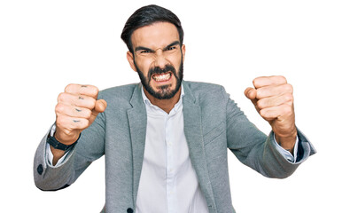 Young hispanic man wearing business clothes angry and mad raising fists frustrated and furious...