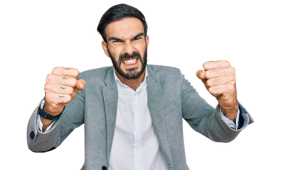 Young hispanic man wearing business clothes angry and mad raising fists frustrated and furious while shouting with anger. rage and aggressive concept.