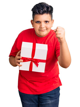 Little boy kid holding gift annoyed and frustrated shouting with anger, yelling crazy with anger and hand raised
