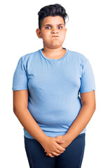 Little boy kid wearing sports workout clothes puffing cheeks with funny face. mouth inflated with air, crazy expression.