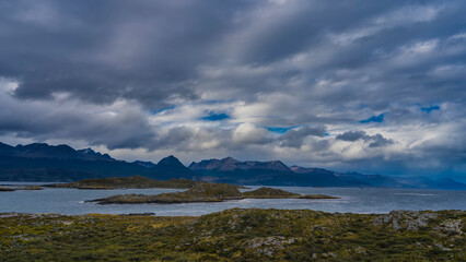 The harsh landscape of southern Patagonia. The islands in the Beagle Channel have low-growing sparse vegetation. In the distance, against the sky and clouds the picturesque mountain range,  Andes