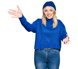 Young caucasian woman wearing wool winter sweater and cap looking at the camera smiling with open arms for hug. cheerful expression embracing happiness.