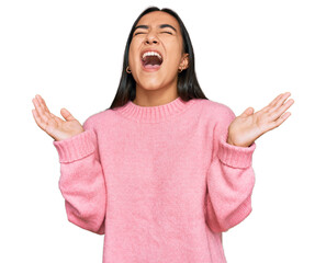 Young asian woman wearing casual winter sweater celebrating mad and crazy for success with arms...