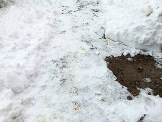Shoveled snow on the path. A path was made on the snow-covered pavement. Severe weather conditions.