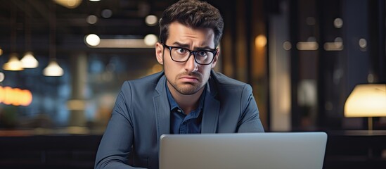 An annoyed young professional using a laptop at work.