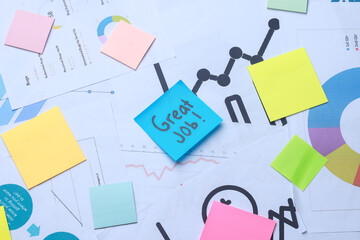 Great Job text on sticky notes with charts diagrams at office work desk.