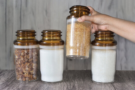 Brown sugar bottle in woman's hand. These are the sucrose sugar made of fructose and glucose from the cane. Help diabetes patient to improve blood sugar levels and control weight