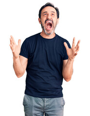 Middle age handsome man wearing casual t-shirt crazy and mad shouting and yelling with aggressive expression and arms raised. frustration concept.