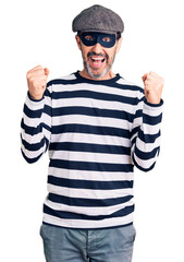 Middle age handsome man wearing burglar mask celebrating surprised and amazed for success with arms...