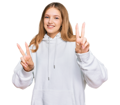 Beautiful young caucasian girl wearing casual sweatshirt smiling looking to the camera showing fingers doing victory sign. number two.
