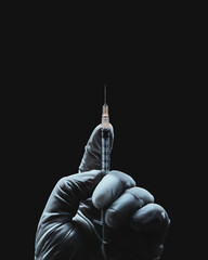 Hand in medical glove holding a syringe on a dark background. Injecting a drug.