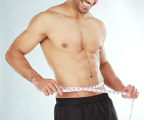 Measuring tape, stomach and fitness man in studio with weight loss, progress or bmi control on white background. Body, wellness and male model with waist measurement for diet, detox or sixpack check